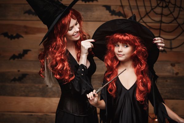 ideias de fantasia para halloween: mãe e filha vestidas com roupa preta usando chapéu pontudo e perucas ruivas